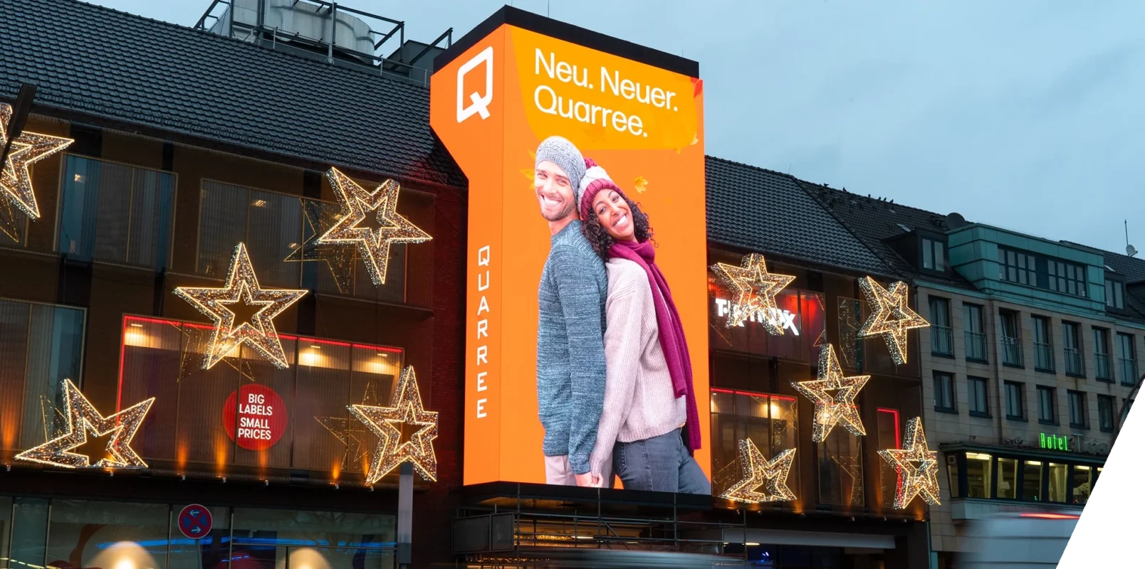 Das Bild zeigt das Wandsbeker Quarree mit einer großen LED, die angepasst an das Gebäude installiert wurde. Die LED zeigt Inhalte über das Einkaufszentrum.