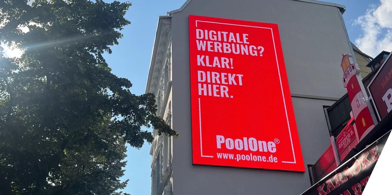 Eine hochformatige LED Wall hängt an einer seitlichen Hauswand.